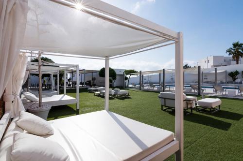 a group of white beds on a green lawn at Hotel Spa Calagrande Cabo de Gata in Las Negras