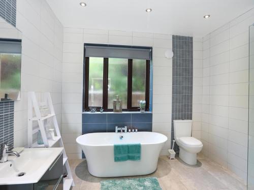 a white bathroom with a tub and a toilet at Gwylan Uchaf in Y Felinheli