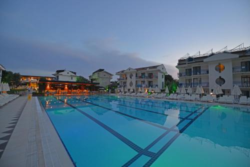 a large swimming pool with chairs and some buildings at Belcekum Beach Hotel in Oludeniz