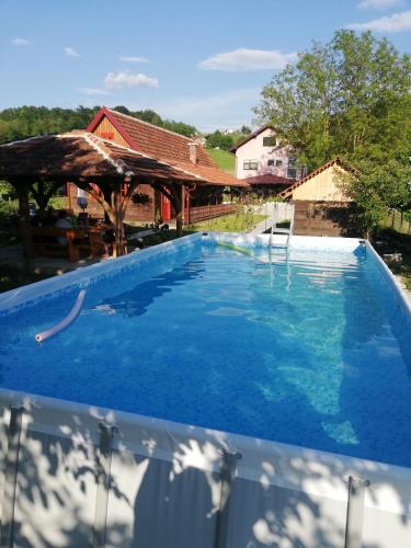 a large blue swimming pool with a house in the background at Pod orehom drvena kuća i sauna in Krapina