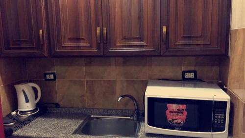 a kitchen counter with a microwave and a sink at Al Tawheed Hotel Apartments in Amman