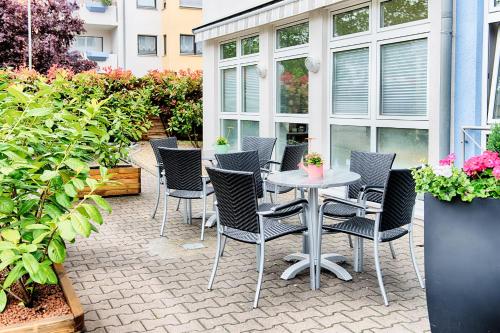 a patio with a table and chairs and plants at ACHAT Hotel Frankenthal in der Pfalz in Frankenthal
