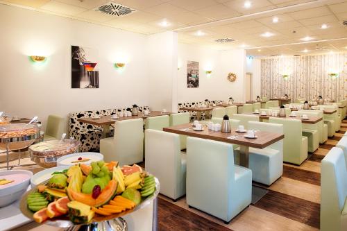 a restaurant with tables and chairs and a plate of food at ACHAT Hotel Frankenthal in der Pfalz in Frankenthal