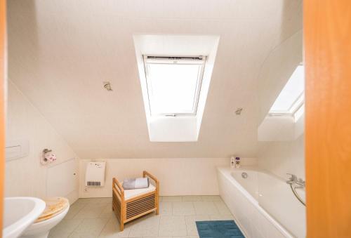 uma casa de banho com uma clarabóia, uma banheira e um lavatório. em Ferienwohnung am Bauernhof em Oederan