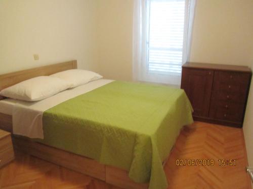 a bedroom with a bed with a green blanket and a dresser at ROBI in Kraljevica