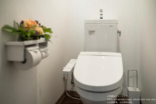 a white toilet in a bathroom with a flower arrangement at Stay SAKURA Kyoto Fuga in Kyoto