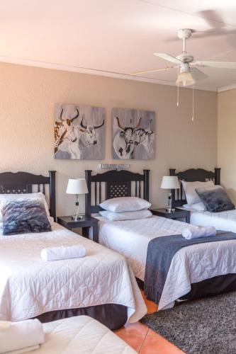 two beds in a bedroom with paintings on the wall at Tzaneen Arborpark Lodge in Tzaneen
