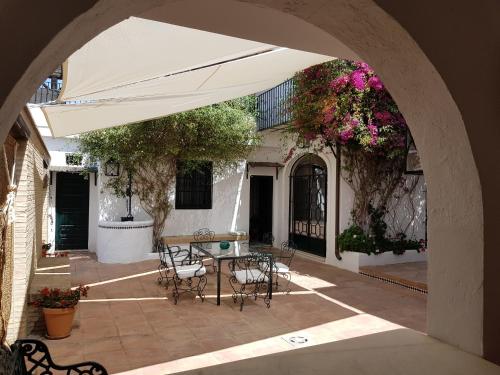 an outdoor patio with an umbrella and tables and chairs at Lince Casa Rural in El Rocío