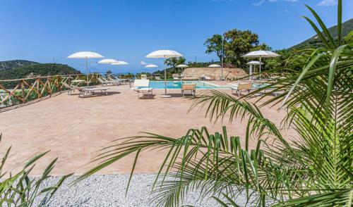 a pool with chairs and umbrellas on a beach at Villa Ginevra Resort Agrituristico in Ficarra