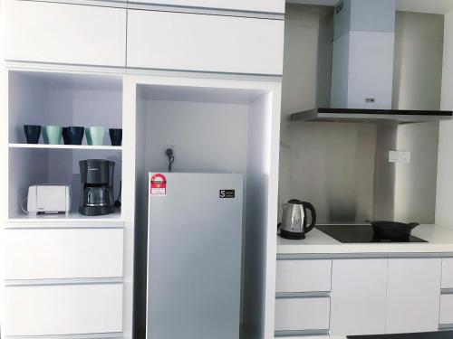 a kitchen with white cabinets and a refrigerator at Mid Valley Southkey Mosaic Cozy Suite at Johor Bahru in Johor Bahru