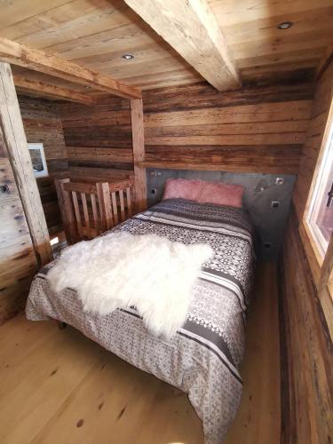 une chambre avec un lit dans une cabane en rondins dans l'établissement Mazot de Joe avec son hammam entre la Clusaz et Annecy, à Thônes