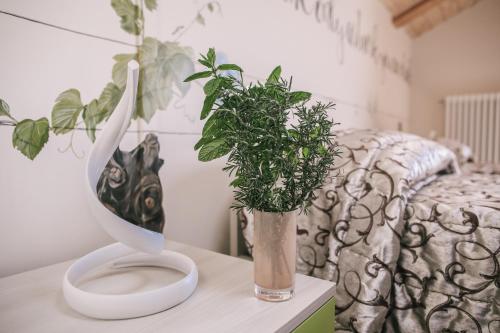a plant in a vase on a table next to a bed at Ca' Colomba in San Damiano dʼAsti