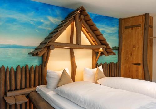 two beds in a room with a painting of the ocean at Landgasthof Paradies in Frickingen