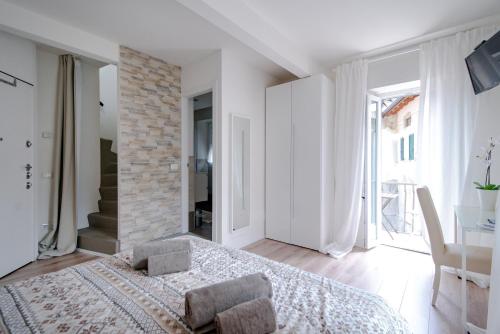 a white bedroom with a bed and a brick wall at Laglio Apartment Above George in Laglio