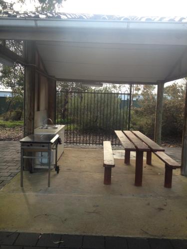 a picnic table and bench under a pavilion with a grill at Parndana Hotel Cabins in Parndana