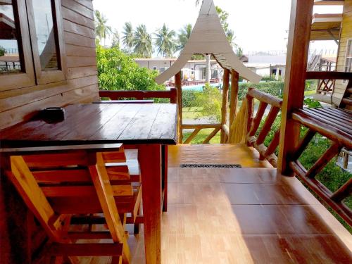 a wooden table and chairs on a porch with a bench at The Ford SunSet Beach Resort in Wok Tum