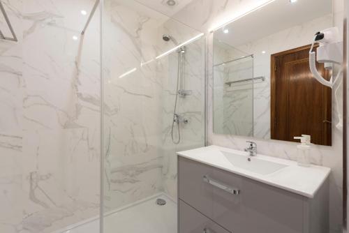 a white bathroom with a sink and a shower at LovelyStay - Heritage Collection House with 4Bedrooms in Porto