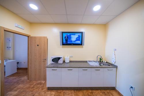 um quarto de hospital com um lavatório e uma televisão na parede em A Corticela em Vilanova de Arousa