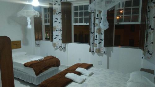 a bedroom with two beds and windows with towels at O Pouso Sobrado in Mucugê