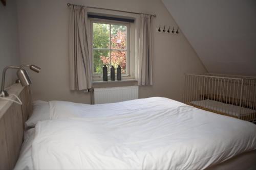 a white bed in a bedroom with a window at Groepsboerderij 20 pers. in Voorthuizen