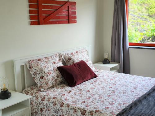 a bedroom with a bed with a pillow and a window at Casinha de Nesquim in Calheta de Nesquim