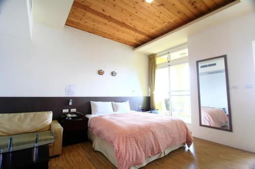 a bedroom with a bed and a chair and a mirror at Sunnydale B&B in Ren'ai
