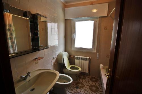 a bathroom with a sink and a toilet and a window at Casa Ardaña in Carballo