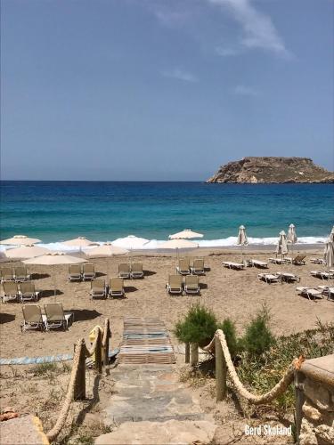 a beach with chairs and umbrellas and the ocean at Aegean View Studios in Lefkos Karpathou