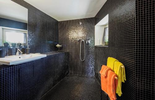 a black tiled bathroom with a shower and a sink at B&B Contemporain Le Jardin in Vaison-la-Romaine
