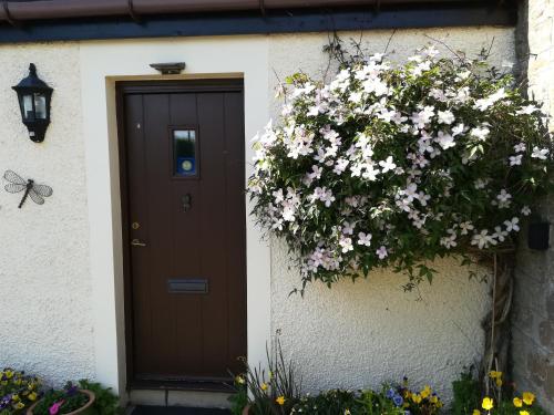 uma porta com flores ao lado de uma casa em Midkinleith Farm Holiday Cottage em Edinburgo