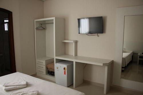 a bedroom with a desk and a tv on the wall at Hotel Alzira Imperial in São Lourenço