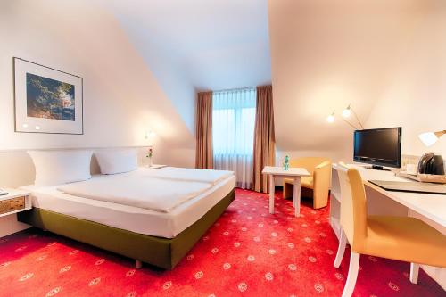 a hotel room with a bed and a desk at ACHAT Hotel Schwetzingen Heidelberg in Schwetzingen