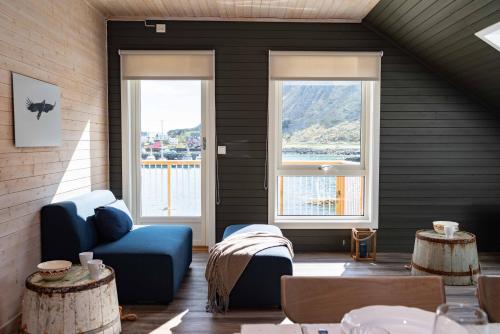 a room with two windows and a blue couch and tables at Hemmingodden Lodge in Ballstad