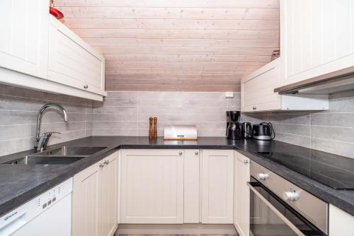 a kitchen with white cabinets and a sink at Hemmingodden Lodge in Ballstad
