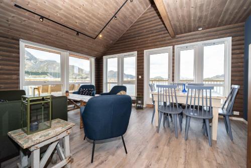a dining room with a table and chairs and windows at Hemmingodden Lodge in Ballstad