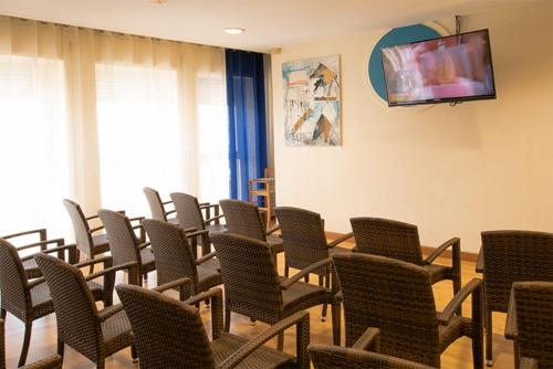 ネットゥーノにあるHotel Scacciapensieriの椅子、テーブル、テレビが備わる客室です。
