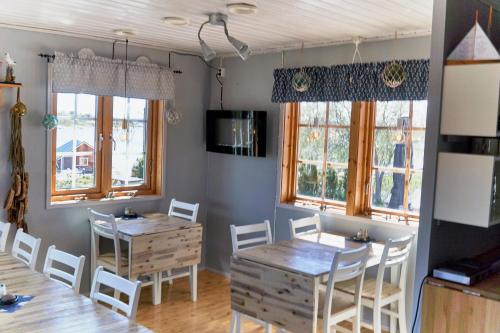 uma sala de jantar com duas mesas e cadeiras e janelas em Kumlinge Stugor em Kumlinge