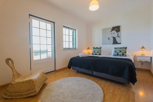 a bedroom with a bed and a chair and a window at Refugio da Longueira in Longueira