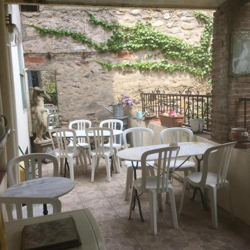 a patio with white tables and chairs and a stone wall at Poppys Chambres d'Hotes in Céret