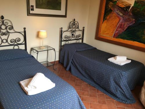 チェッレート・グイーディにあるIl Borgherinoのベッド2台、ランプ、絵画が備わる部屋
