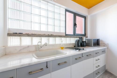 a kitchen with white cabinets and a sink and windows at Red Beachfront Apartment in Kokkíni Khánion
