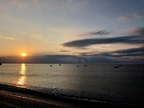 a sunset on the beach with boats in the water at Palazzo Durante in Letojanni