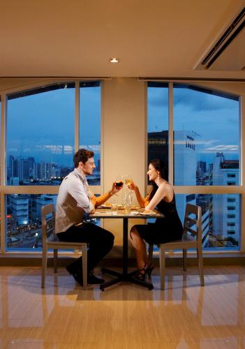 a man and woman sitting at a table with wine glasses at The Quarter Hualamphong by UHG in Bangkok
