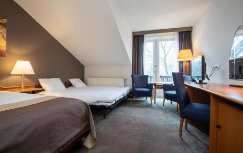 Fletcher Hotel-Restaurant Klein Zwitserland في هيلسوم: غرفه فندقيه بسرير ومكتب وكراسي