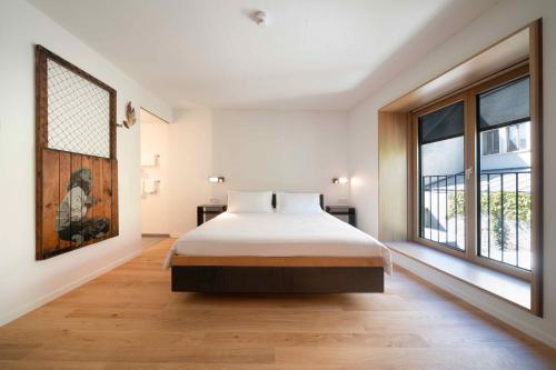 una camera da letto con un letto e una grande finestra di SET Hotel.Residence by Teufelhof Basel a Basilea