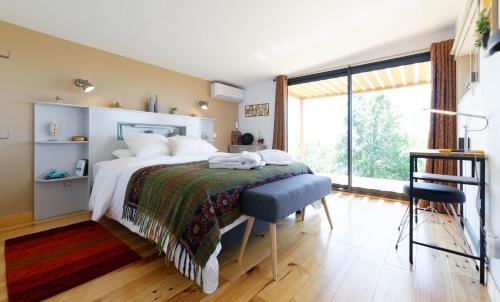 a bedroom with a bed and a large window at Chambre d'hôtes de charme à la Maison Bleue in Savignac-Mona