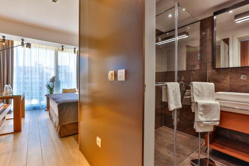 uma casa de banho com um chuveiro, um lavatório e uma cama em Hotel Fagus by Aycon em Budva