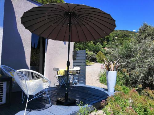 an umbrella on a deck with a table and chairs at Chez Jeff & Aurélie in Draguignan