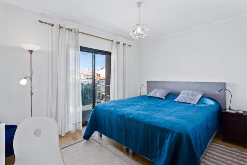a bedroom with a blue bed and a large window at Casa Saura in Alvor