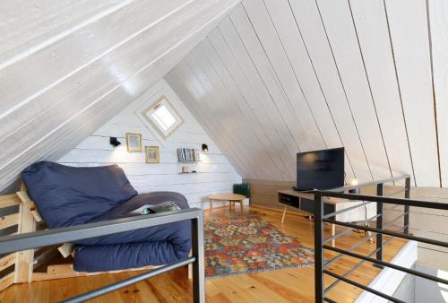 a room with a couch and a tv in a attic at Chalet de charme climatisé, son Jacuzzi - SPA privatif et la piscine de la Maison Bleue du Gers in Savignac-Mona